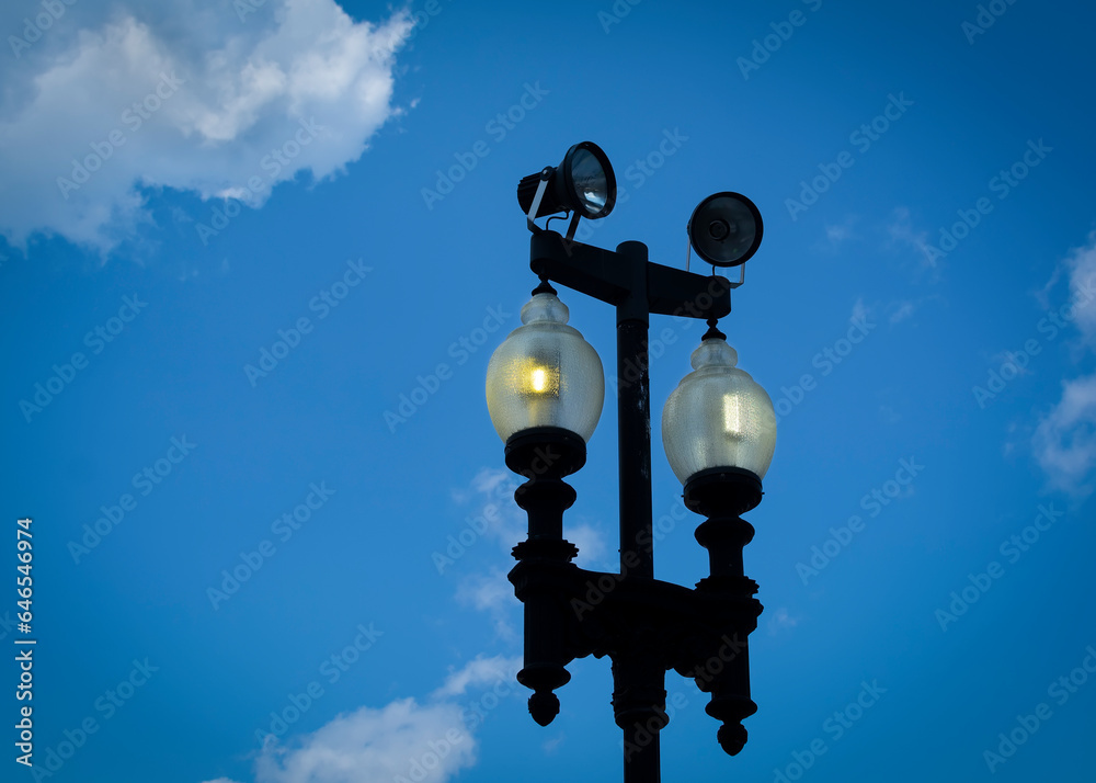 Lit lamppost silhouette against blue sky, Boston, USA Lit lamppost silhouette against blue sky, Boston, USA