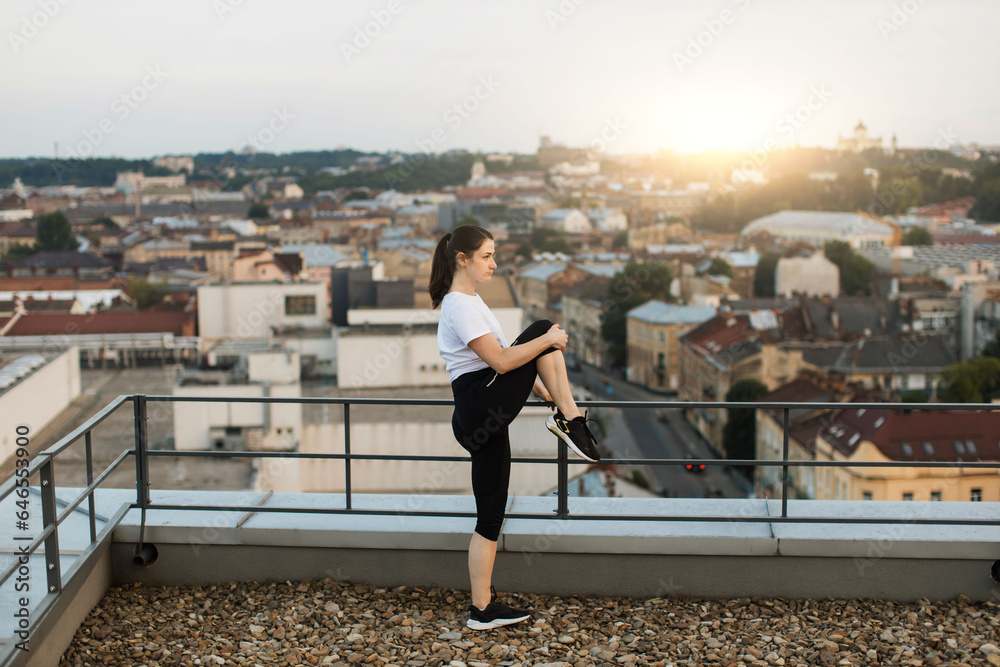 Athlete stretching knees during warming-up on roof terrace