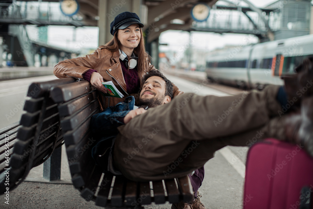 Young couple traveling and waiting for the train at a train station with their suitcases