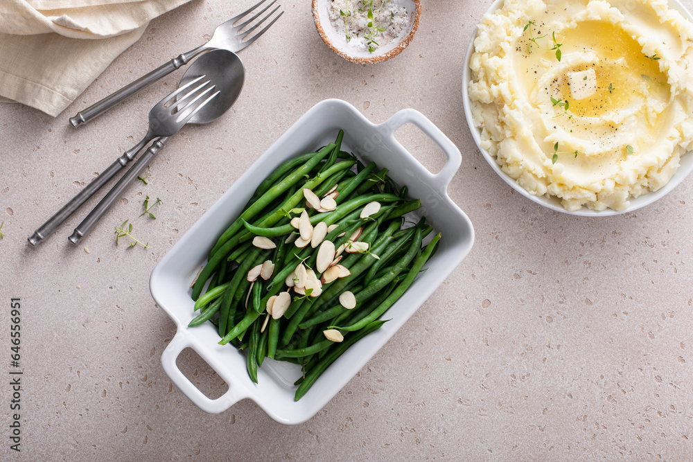 Green beans topped with almonds in a baking dish, traditional side dish for dinner or celebration - obrazy, fototapety, plakaty 