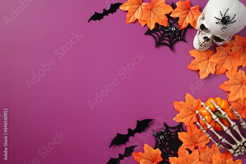Halloween greeting card design. Halloween frame made of skull spiders  webs  fall maple leaves  bats on purple background. Flat lay  top view  copy space.