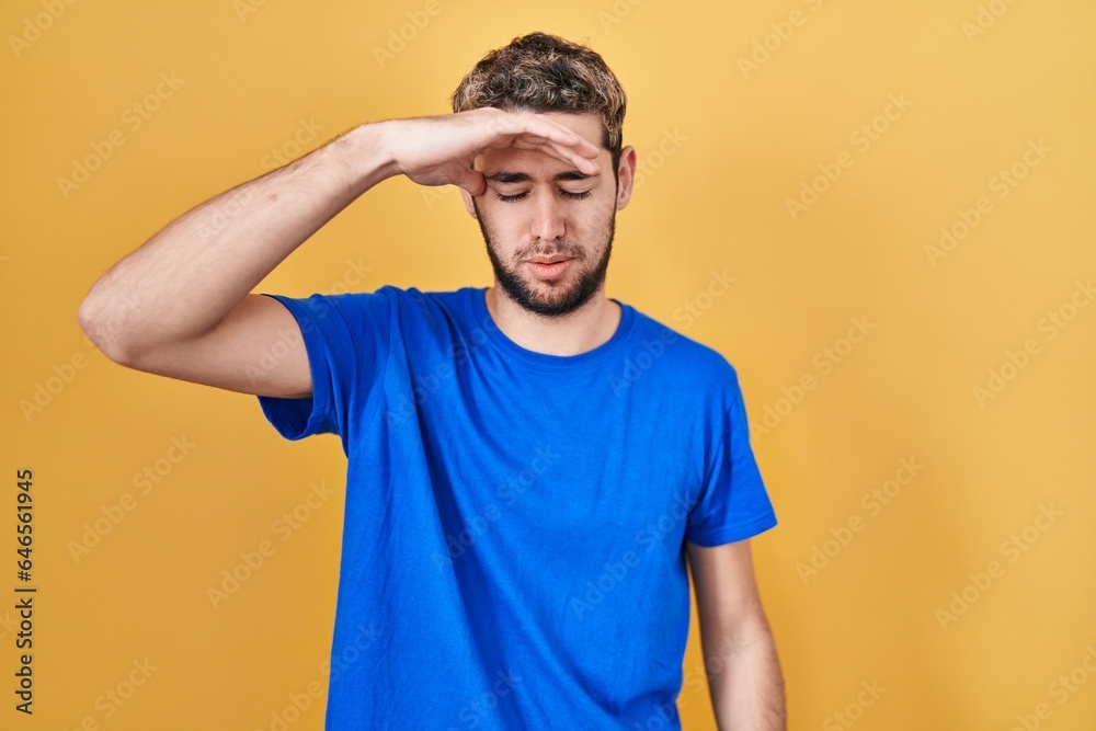 Hispanic man with beard standing over yellow background worried and stressed about a problem with hand on forehead, nervous and anxious for crisis Hispanic man with beard standing over yellow background worried and stressed about a problem with hand on forehead, nervous and anxious for crisis