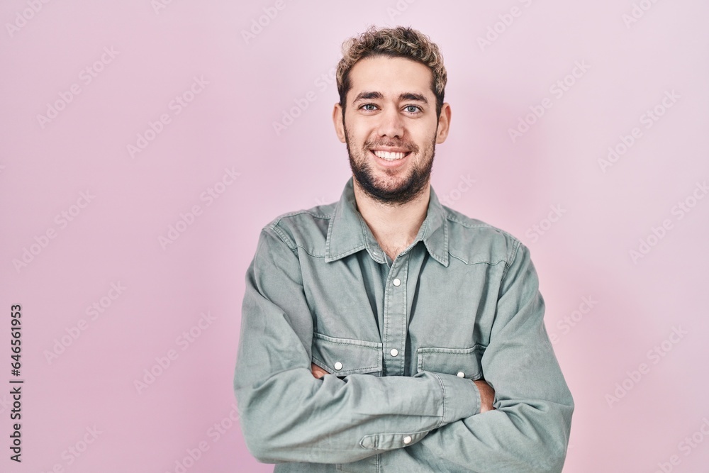 Obraz premium Hispanic man with beard standing over pink background happy face smiling with crossed arms looking at the camera. positive person.