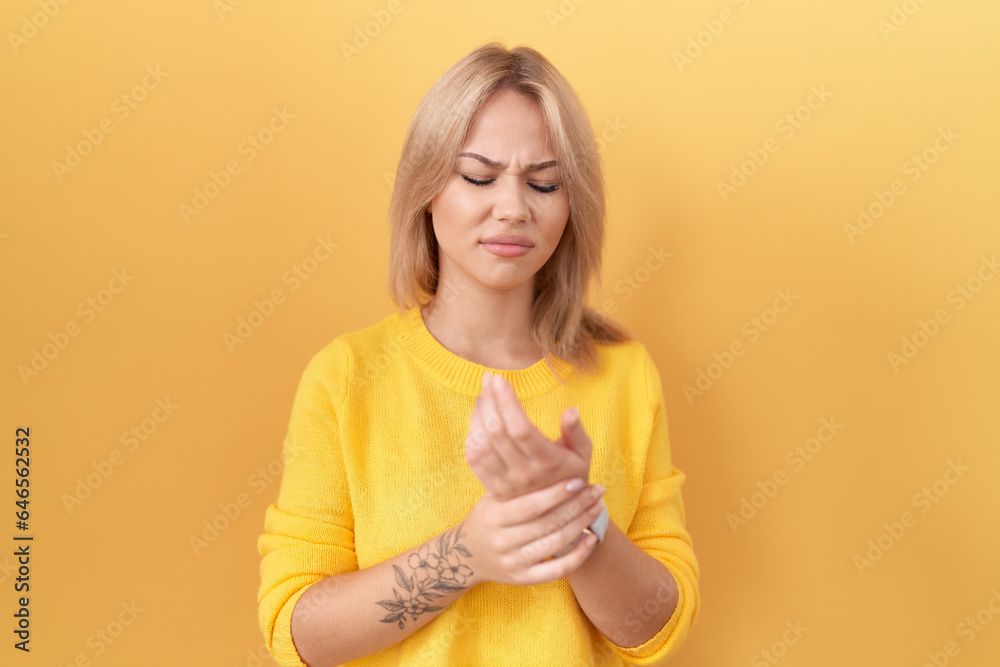 Young caucasian woman wearing yellow sweater suffering pain on hands and fingers, arthritis inflammation Young caucasian woman wearing yellow sweater suffering pain on hands and fingers, arthritis inflammation