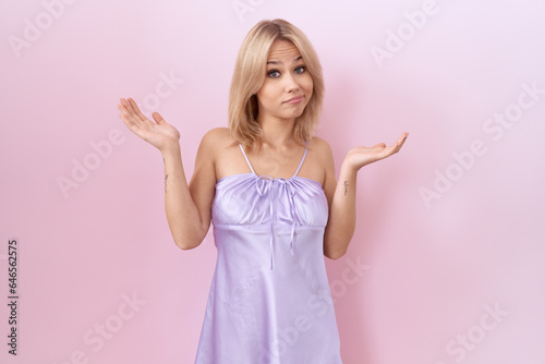 Young caucasian woman wearing lingerie dress clueless and confused expression with arms and hands raised. doubt concept.