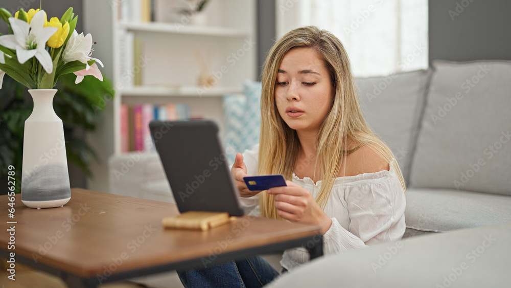 Young blonde woman having video call shopping with credit card at home