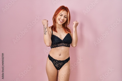 Young caucasian woman wearing lingerie over pink background celebrating surprised and amazed for success with arms raised and eyes closed. winner concept.