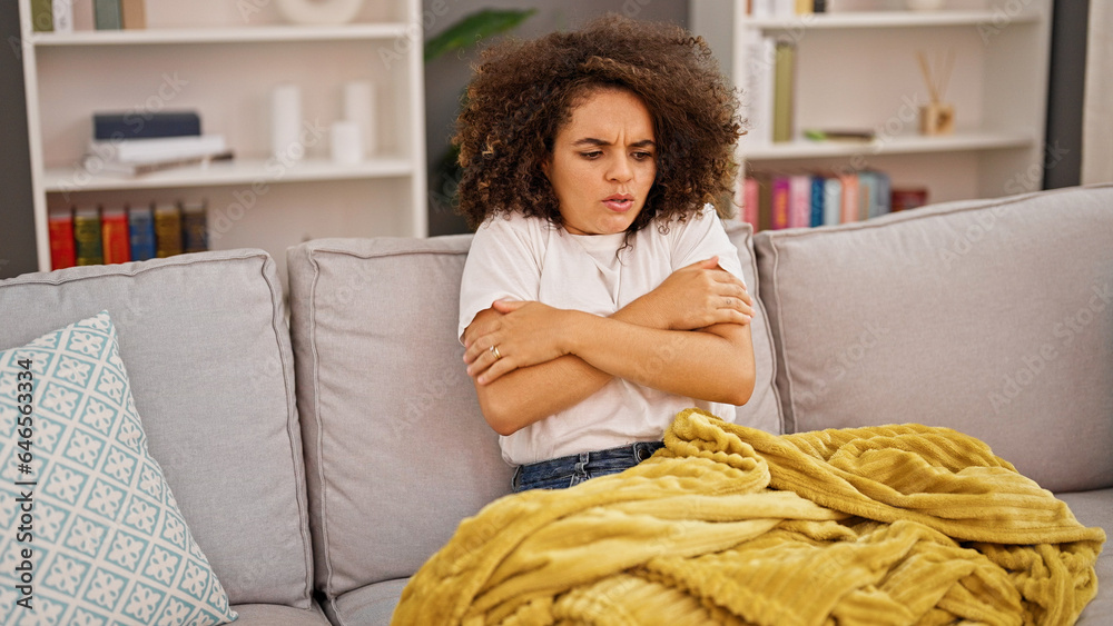 Young beautiful hispanic woman feeling cold covered with blanket at home Young beautiful hispanic woman feeling cold covered with blanket at home