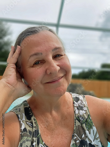 senior adult woman relaxing beside swimming pool photo