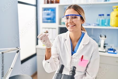 Young hispanic woman scientist looking sample at laboratory