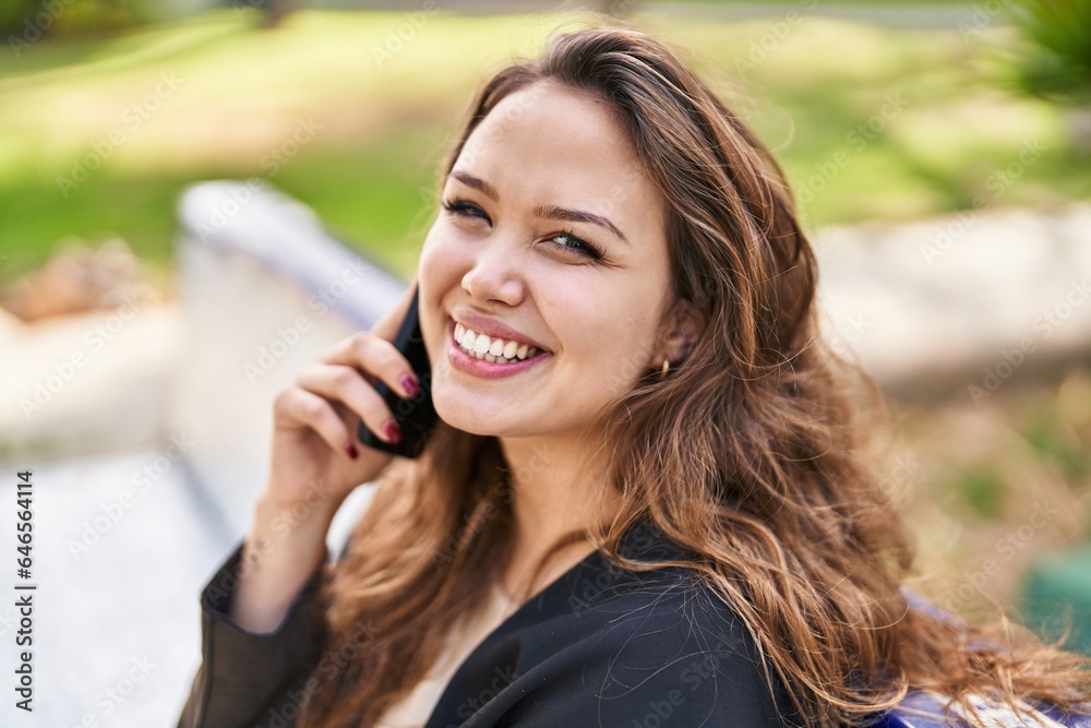 Young beautiful hispanic woman talking on the smartphone sitting on bench at park Young beautiful hispanic woman talking on the smartphone sitting on bench at park