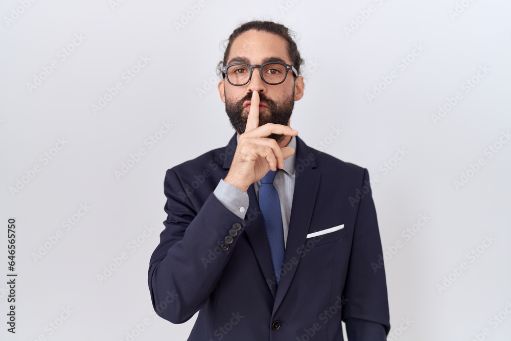 Hispanic man with beard wearing suit and tie asking to be quiet with finger on lips. silence and secret concept. Hispanic man with beard wearing suit and tie asking to be quiet with finger on lips. silence and secret concept.