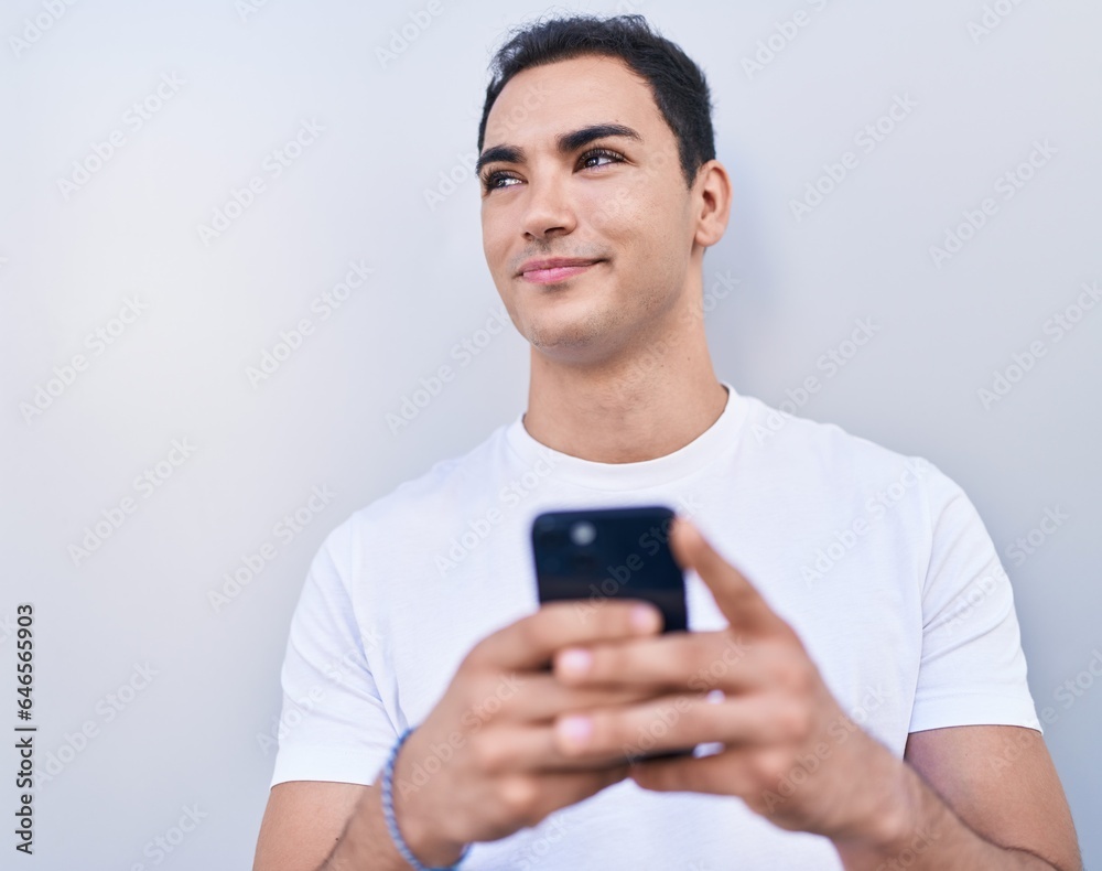 Young hispanic man smiling confident using smartphone over isolated white background Young hispanic man smiling confident using smartphone over isolated white background