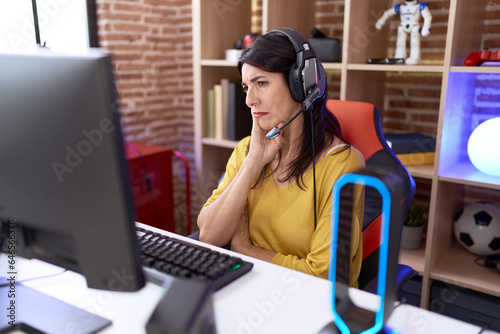 Middle age hispanic woman playing video games using headphones thinking looking tired and bored with depression problems with crossed arms. © Krakenimages.com