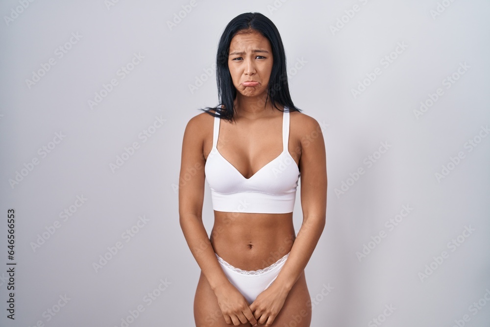 Fototapeta premium Hispanic woman wearing lingerie depressed and worry for distress, crying angry and afraid. sad expression.