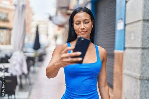Young beautiful latin woman smiling confident making selfie by the smartphone at street