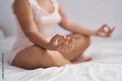 Young woman doing yoga exercise sitting on bed at bedroom