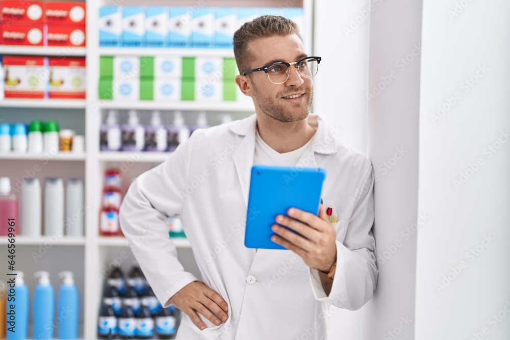 Young caucasian man pharmacist using touchpad working at pharmacy Young caucasian man pharmacist using touchpad working at pharmacy