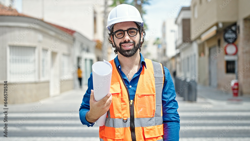 Young hispanic man architect smiling confident holding blueprints at construction place Young hispanic man architect smiling confident holding blueprints at construction place