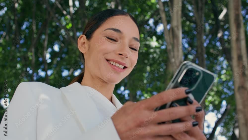 Smiling girl reading sms on smartphone standing park close up. Woman messaging Smiling girl reading sms on smartphone standing park close up. Woman messaging