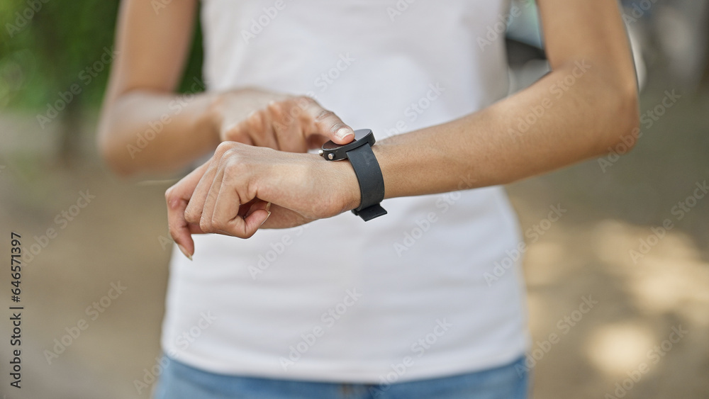 African american woman pointing to watch at park