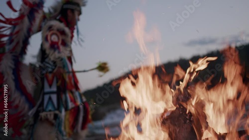 Native American Indigenous Dancing by the fireplace at sunset in Alberta Canada wearing traditional Tsu'Tina Fancy Dance Regalia. Cinematic Footage of Indigenous Fancy Dance at Sunset in Slow motion. photo
