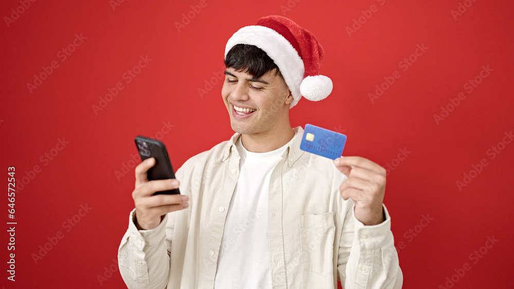 Young hispanic man shopping with smartphone and credit card wearing christmas hat over isolated red background Young hispanic man shopping with smartphone and credit card wearing christmas hat over isolated red background