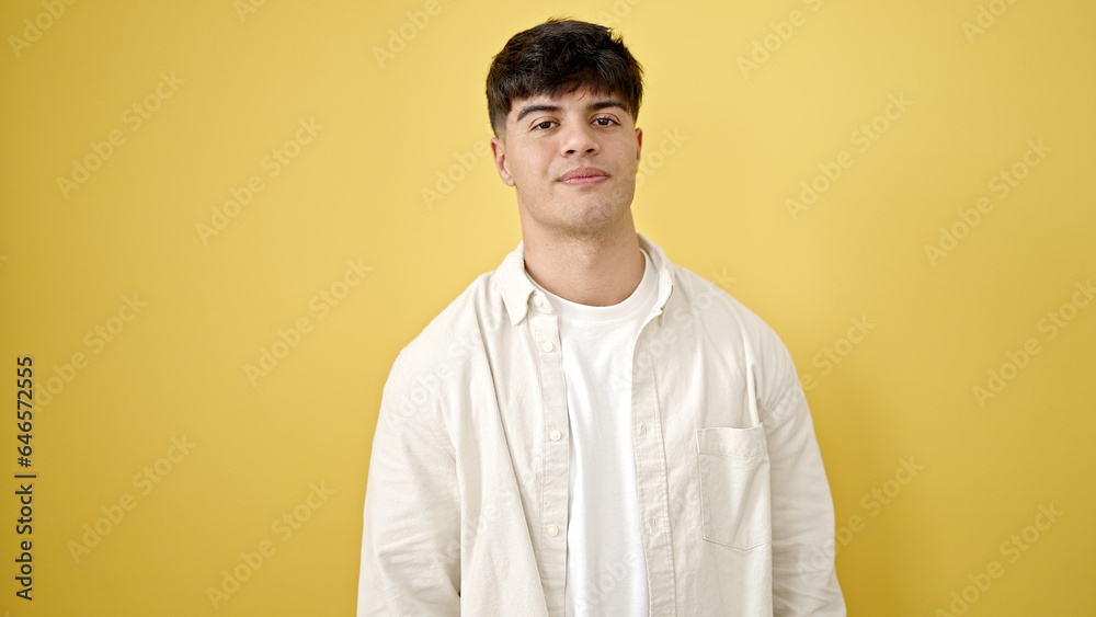 Young hispanic man standing with serious expression over isolated yellow background Young hispanic man standing with serious expression over isolated yellow background