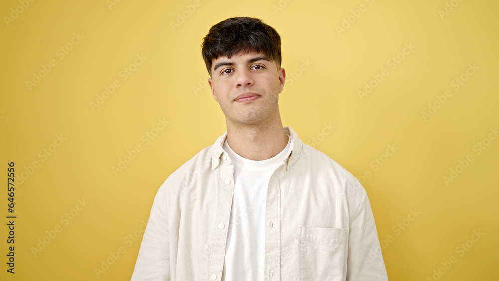 Young hispanic man standing with serious expression over isolated yellow background Young hispanic man standing with serious expression over isolated yellow background