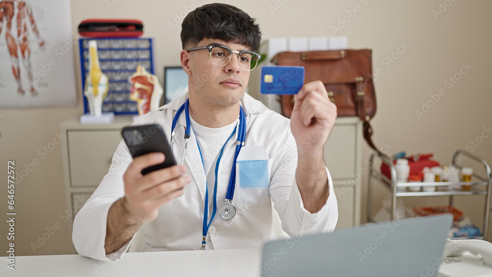 Young hispanic man doctor shopping with smartphone and credit card at clinic