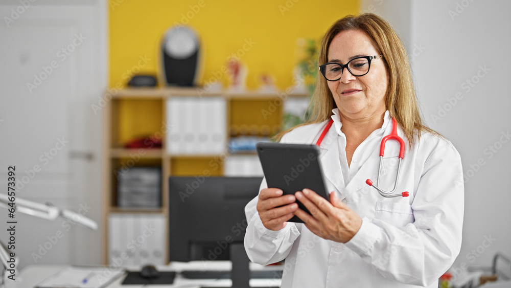 Middle age hispanic woman doctor smiling using touchpad at the clinic Middle age hispanic woman doctor smiling using touchpad at the clinic