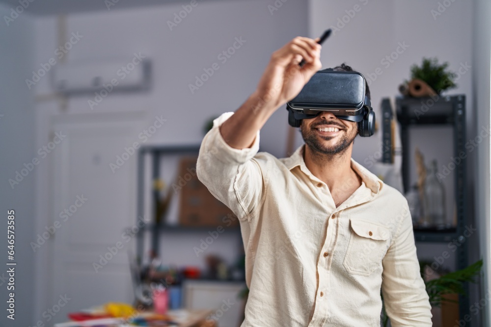 Obraz premium Young hispanic man artist using virtual reality glasses drawing at art studio