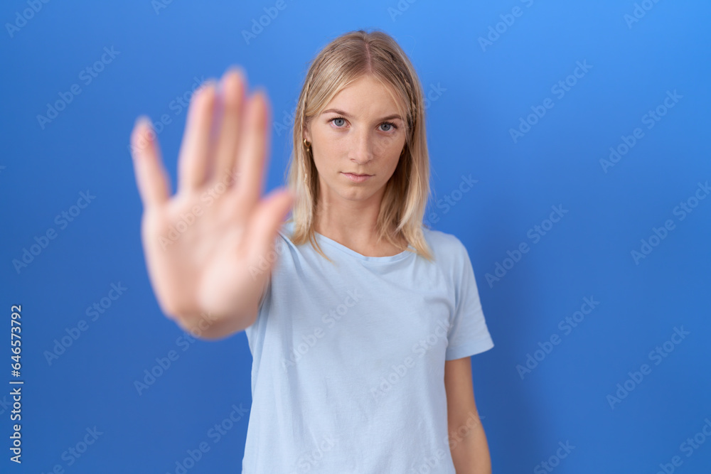 Fototapeta premium Young caucasian woman wearing casual blue t shirt doing stop sing with palm of the hand. warning expression with negative and serious gesture on the face.