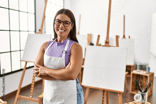 Young beautiful hispanic woman artist smiling confident standing with arms crossed gesture at art studio