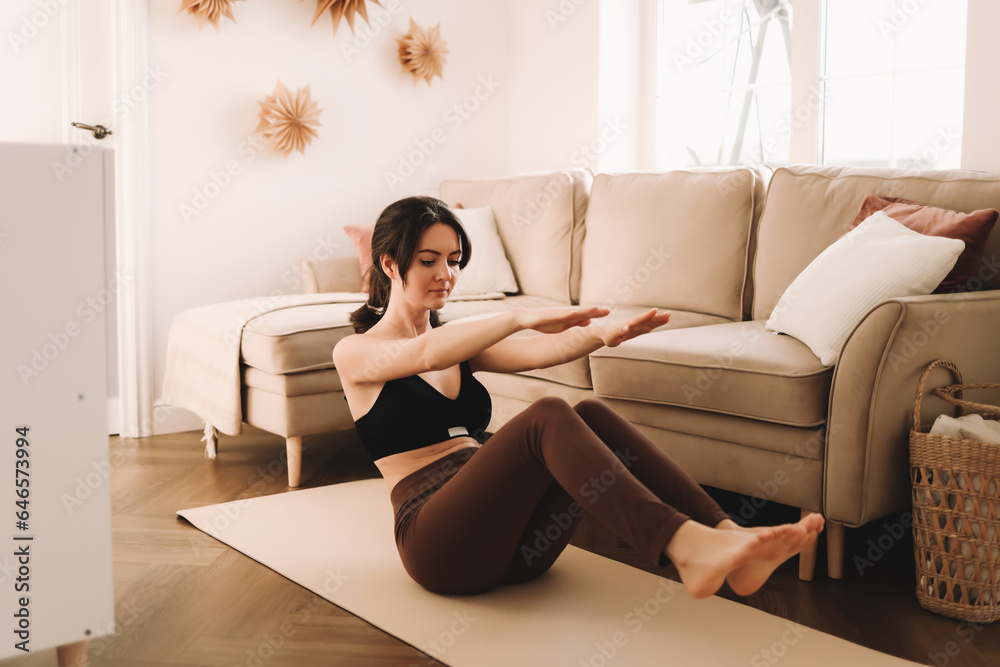 A young fitness woman in sportswear does sports stretching and yoga in the bright interior of the apartment room. Healthy lifestyle. Selective focus A young fitness woman in sportswear does sports stretching and yoga in the bright interior of the apartment room. Healthy lifestyle. Selective focus
