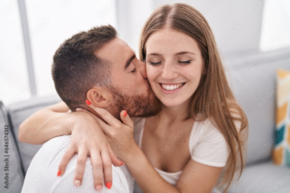 Man and woman couple sitting on sofa kissing at home Man and woman couple sitting on sofa kissing at home