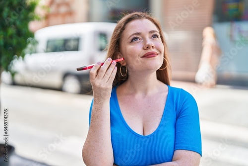 Young redhead woman miling confident listening audio message by the smartphone at street Free Download Young redhead woman miling confident listening audio message by the smartphone at street - GFXLoad