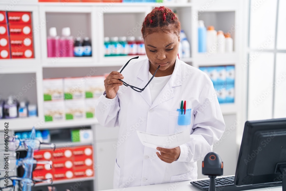 African american woman pharmacist reading prescription at pharmacy