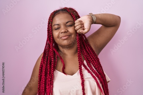 African american woman with braided hair standing over pink background stretching back, tired and relaxed, sleepy and yawning for early morning © Krakenimages.com