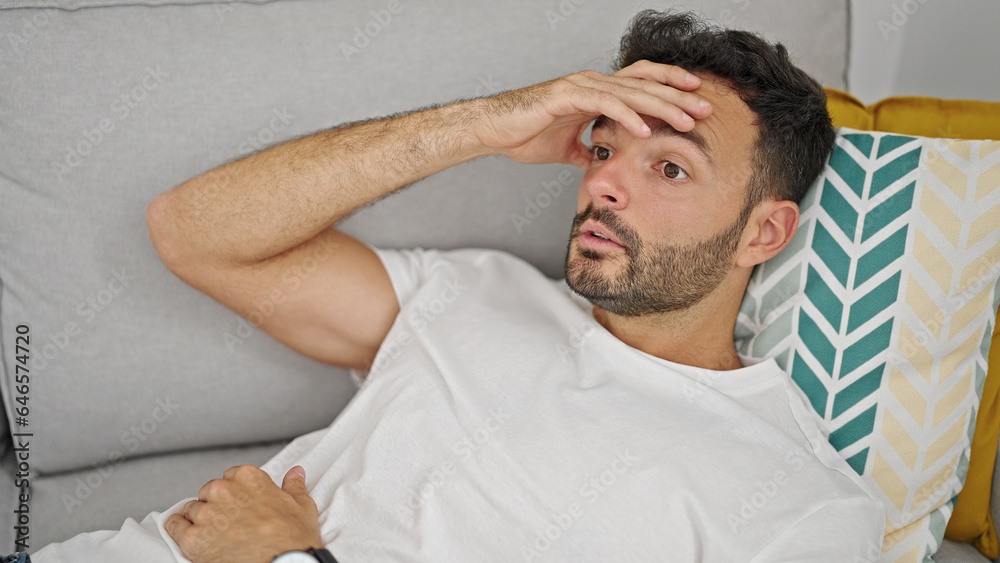 Obraz premium Young hispanic man suffering for headache lying on sofa at home