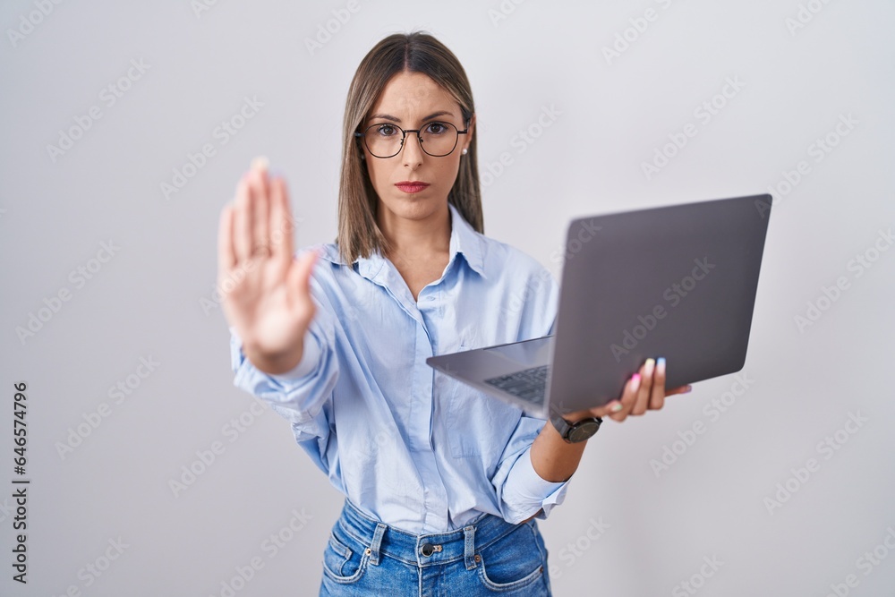 Young woman working using computer laptop doing stop sing with palm of the hand. warning expression with negative and serious gesture on the face. Young woman working using computer laptop doing stop sing with palm of the hand. warning expression with negative and serious gesture on the face.