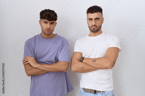 Homosexual gay couple standing over white background skeptic and nervous, disapproving expression on face with crossed arms. negative person.