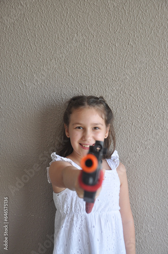 Menina brincando com arma de fogo de brinquedo, tiro ao alvo 