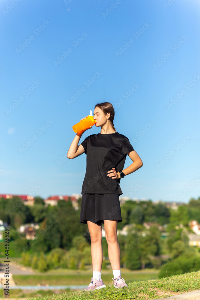 Fit tennage girl runner outdoors holding water bottle.