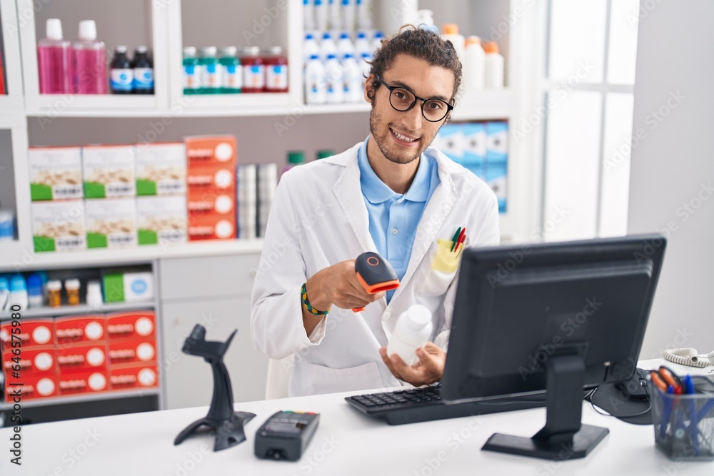 Young hispanic man pharmacist scanning pills bottle at pharmacy