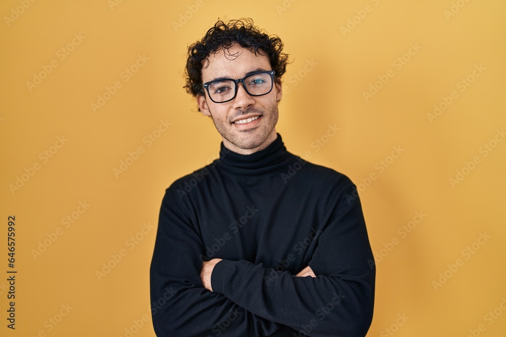 Obraz premium Hispanic man standing over yellow background happy face smiling with crossed arms looking at the camera. positive person.