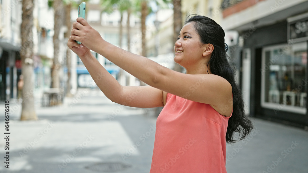 Young chinese woman smiling confident making photo by the smartphone at street