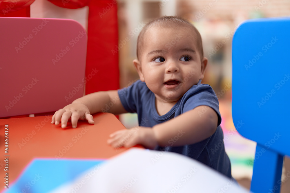 Adorable chinese toddler leaning on table standing at kindergarten Adorable chinese toddler leaning on table standing at kindergarten