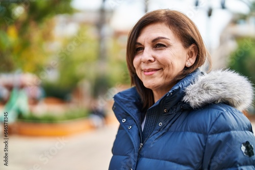 Middle age woman smiling confident looking to the side at park