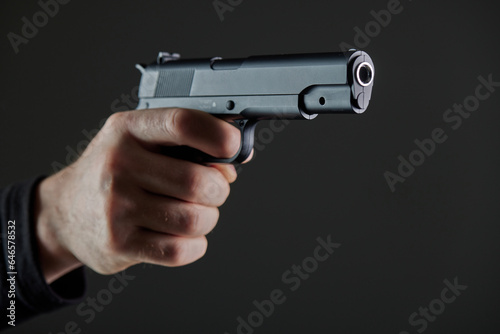 Male hand holding a gun on black background . A gun in a man's hand. defense or attack murderer or armed robber, First person view of a pistol.